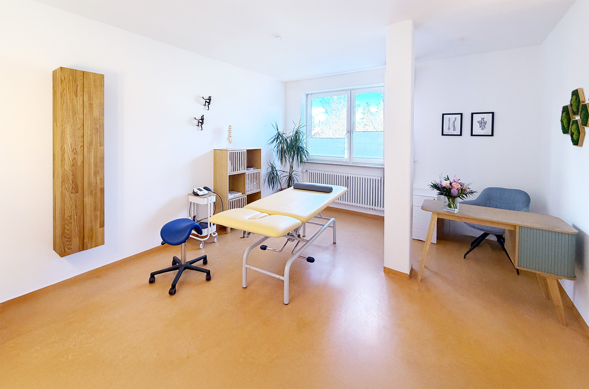 Heller Behandlungsraum der Physiotherapie Isabel Kürzl am Rathausplatz in Grünwald mit Behandlungsliege, Schreibtisch und Naturlicht